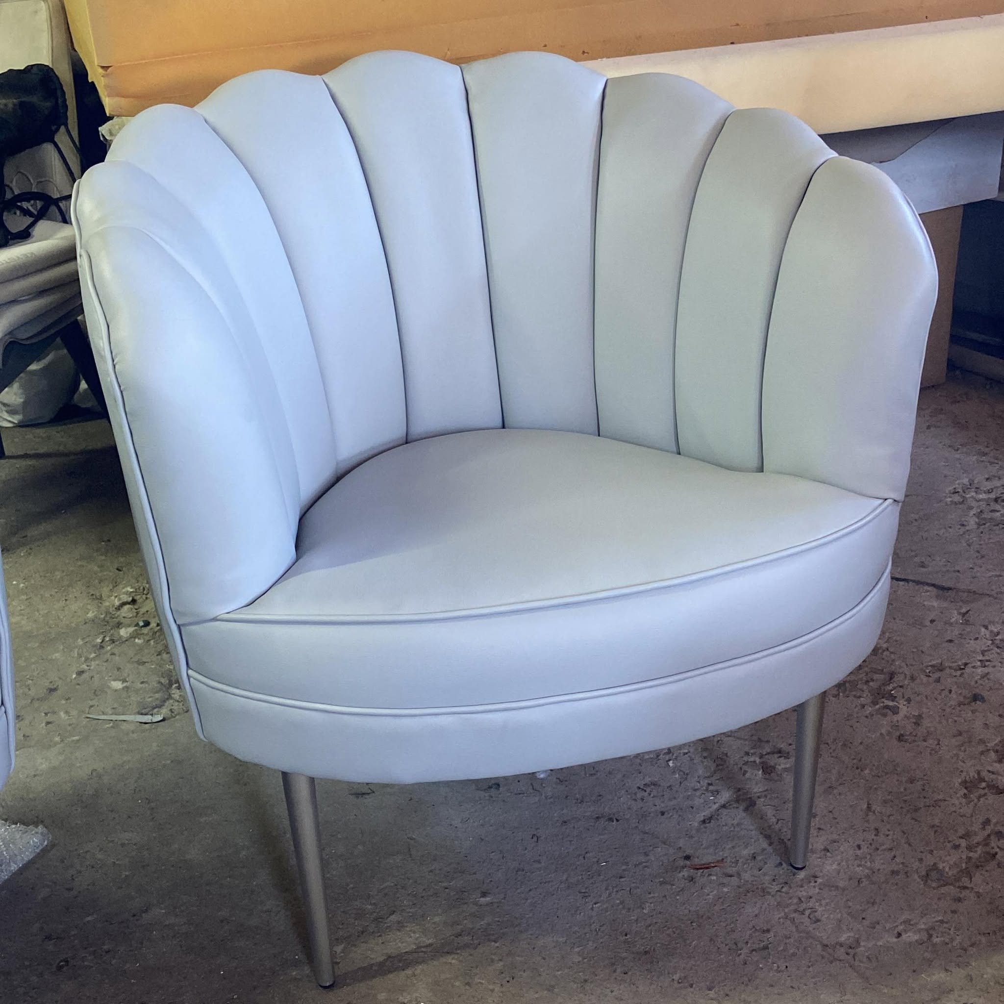 Sillón tipo concha tapizado en piel gris claro