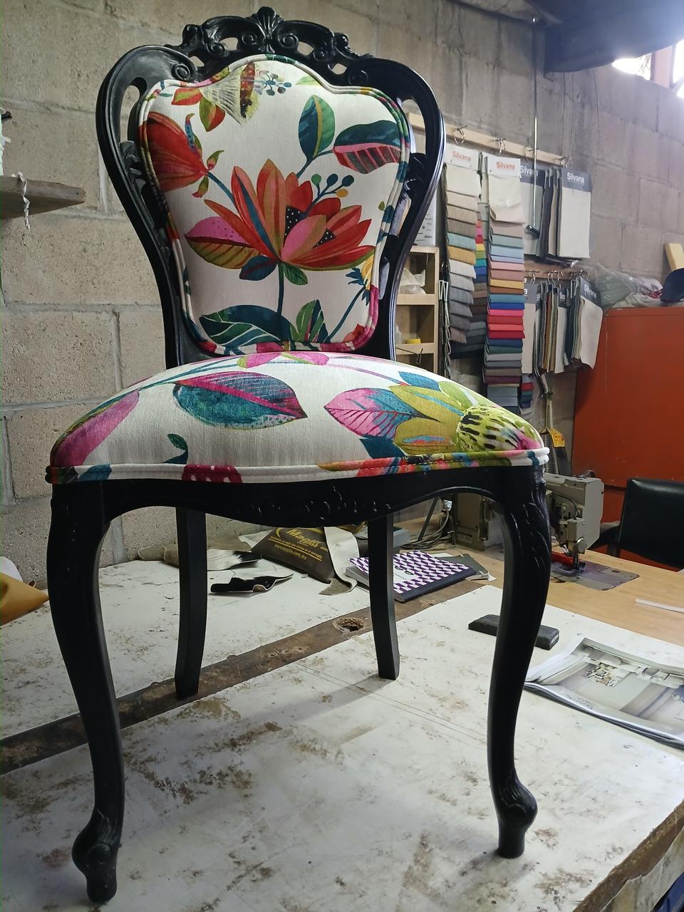 Silla tapizada en tela floral colorida con base negra tallada