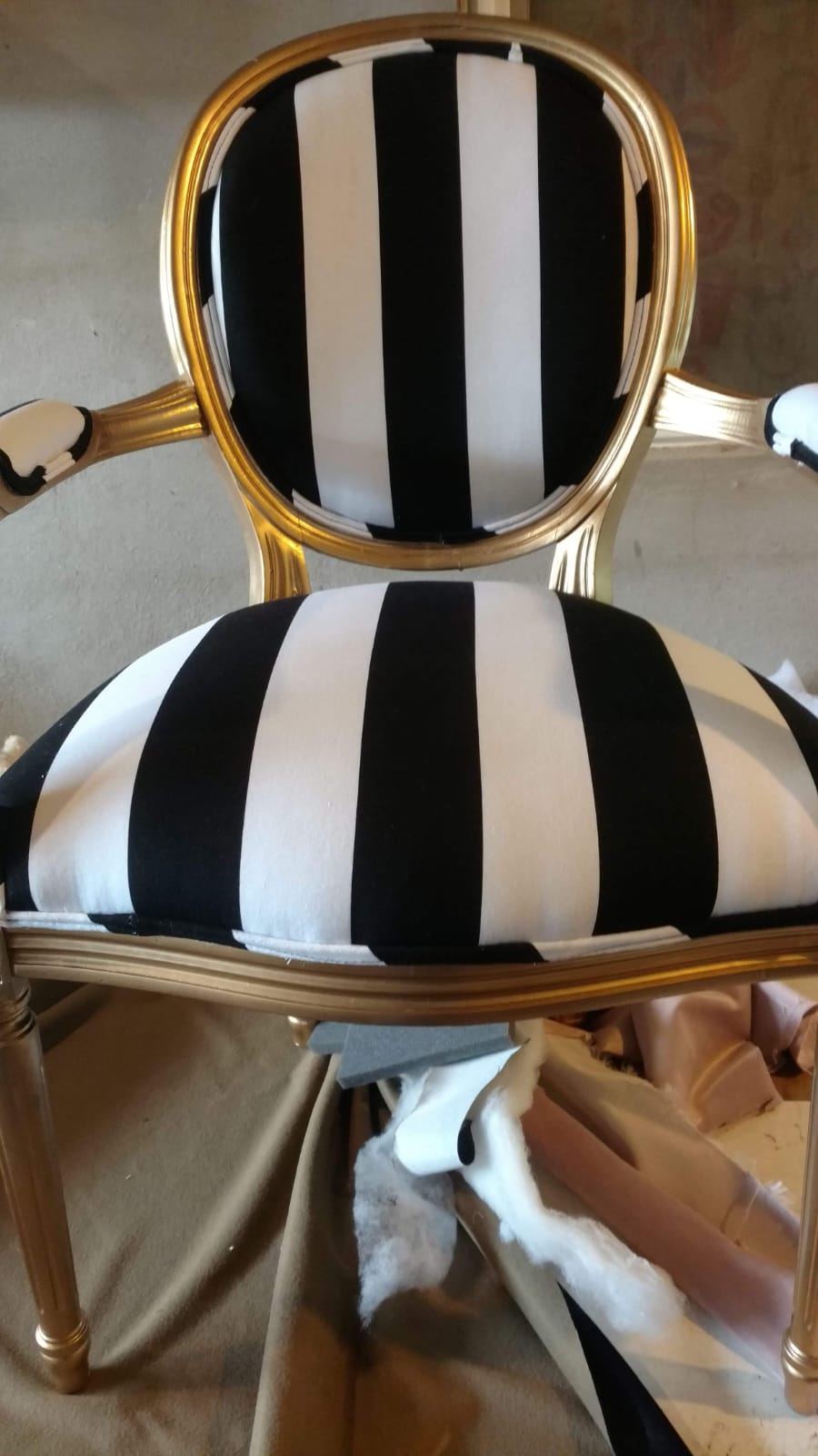 Silla con rayas blancas y negras y estructura dorada