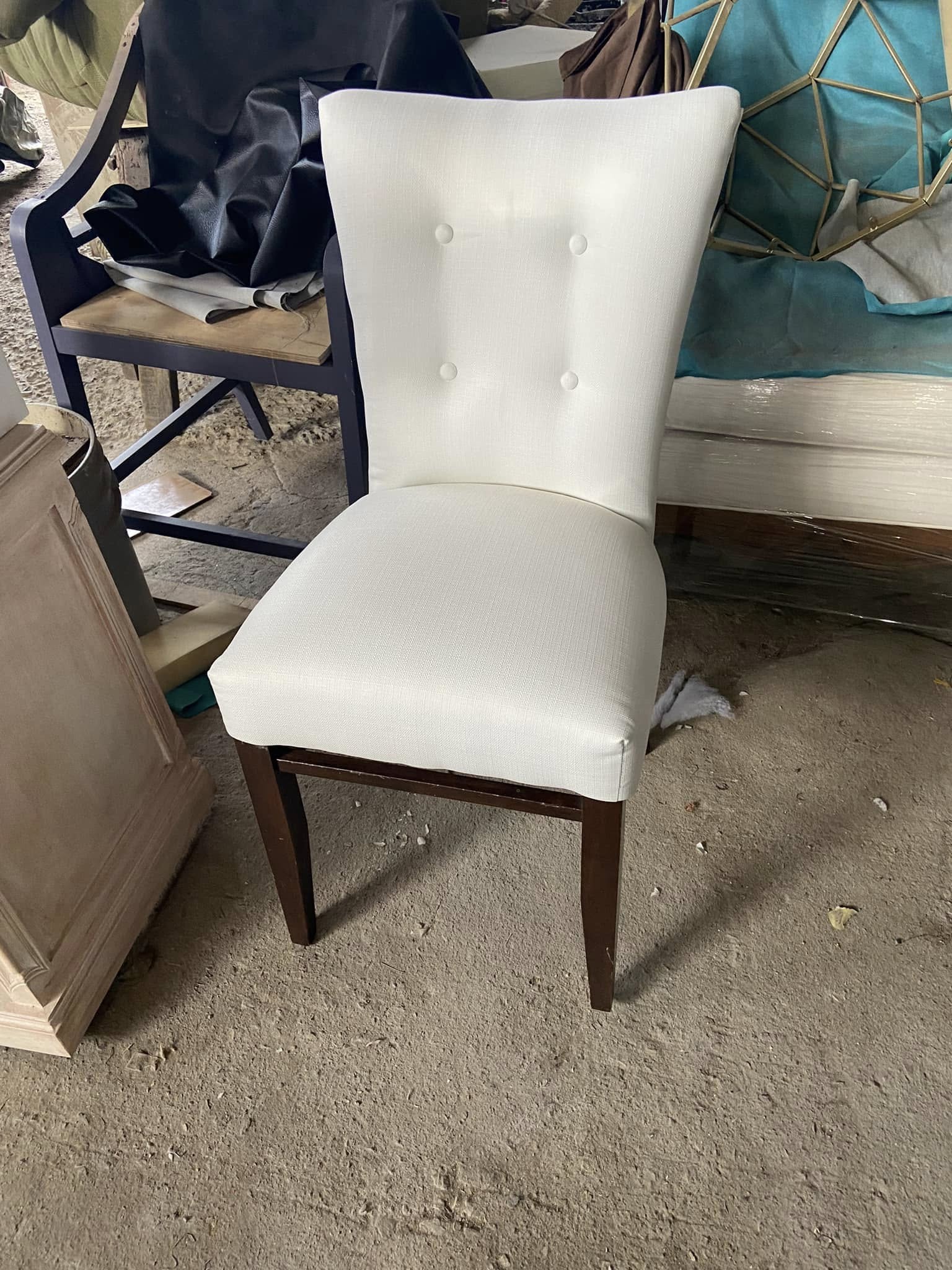 Silla tapizada en blanco con botonadura y patas de madera