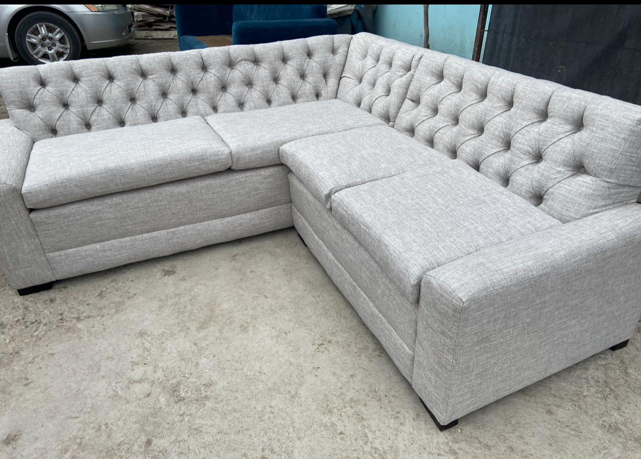 Sillón esquinero tapizado en gris con botonadura